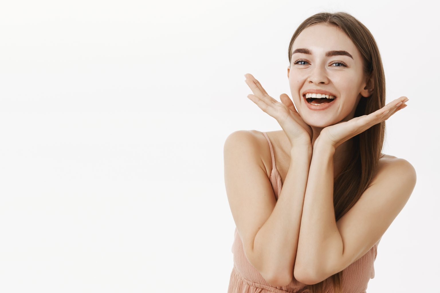 Waist-up shot of beautiful and healthy charming woman with natural beauty holding palms near jawline and smiling broadly pleased with perfect skin condition, posing cheerfully over gray background - Jurnalul Olteniei – Știri din Craiova și Oltenia