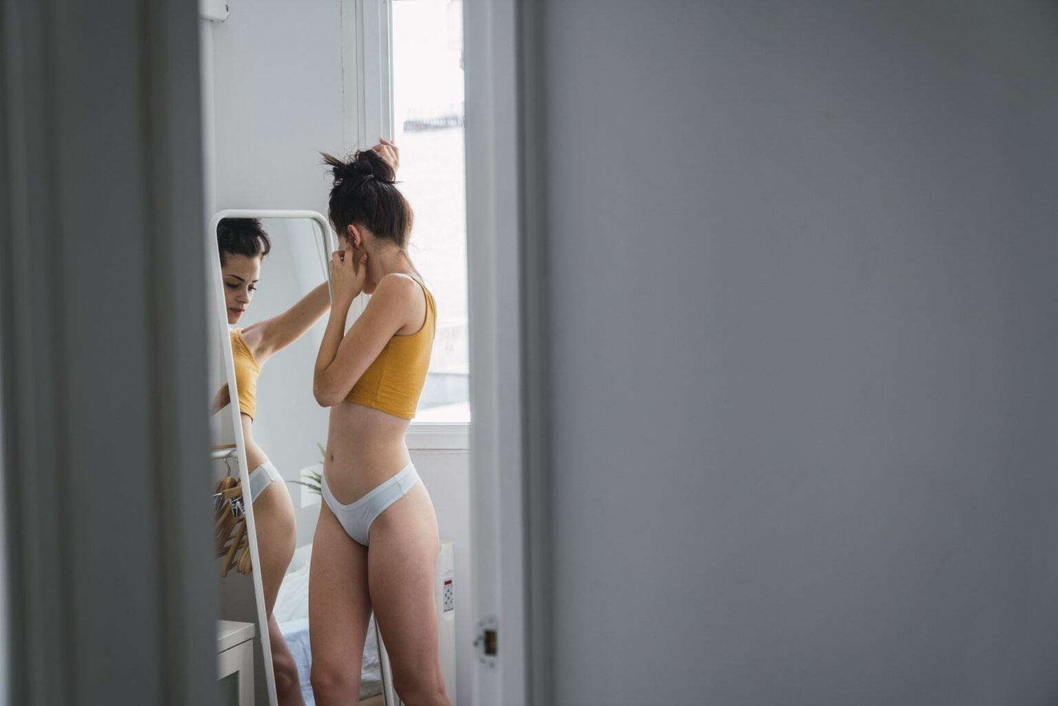 Young woman in underwear at home looking in mirror - Jurnalul Olteniei – Știri din Craiova și Oltenia