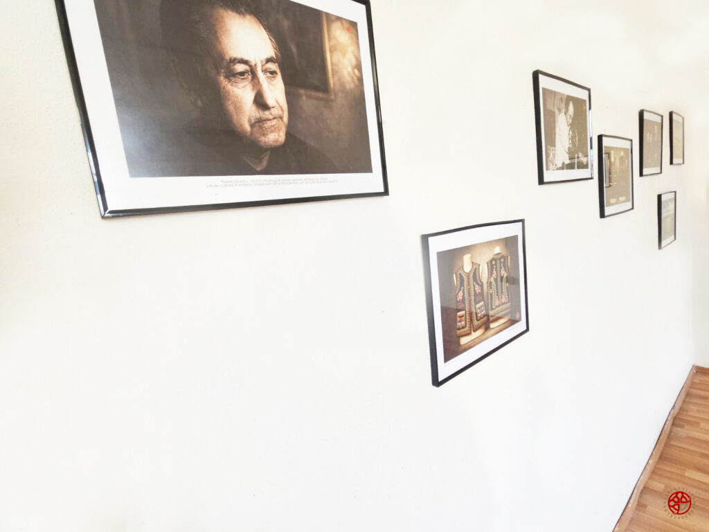 Gallery wall in a bright room with multiple framed photos, including a large portrait on the left and smaller pictures along the wall, hardwood floor visible to the right.