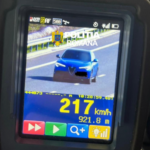 Police speed radar display showing a blue car on a highway, readout 217 km/h with Romanian police branding at the top.