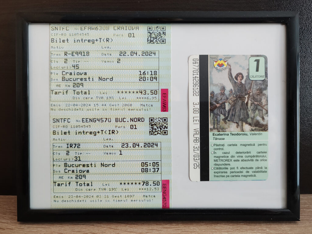 Close-up of a Romanian train ticket and a travel card displayed in a frame, showing printed travel details.