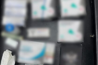 Open black case with several blurred boxes and a small lighter; logos for D.I.C.O.T. and Politia Română visible at top corners, suggesting seized evidence.