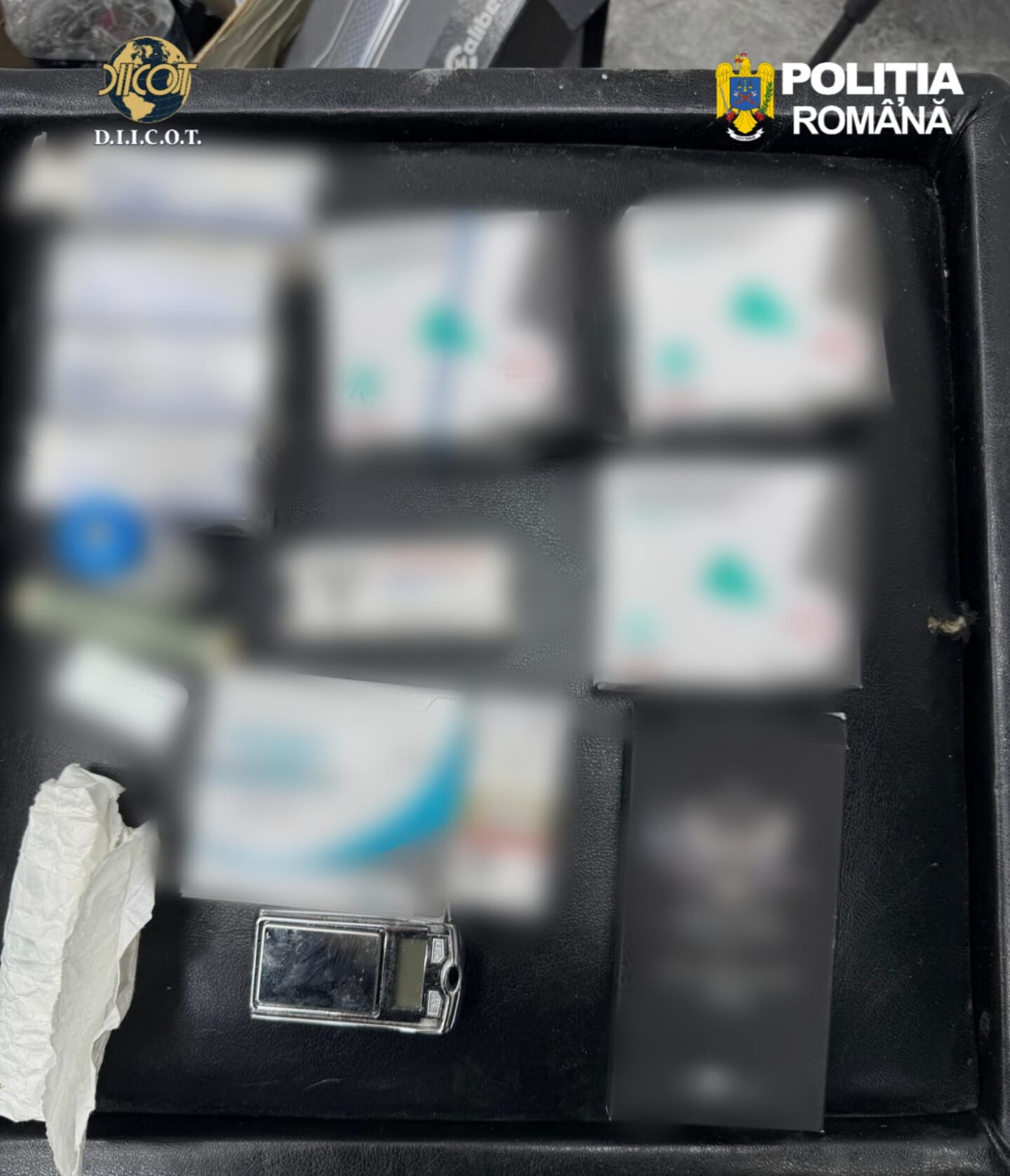 Open black case with several blurred boxes and a small lighter; logos for D.I.C.O.T. and Politia Română visible at top corners, suggesting seized evidence.