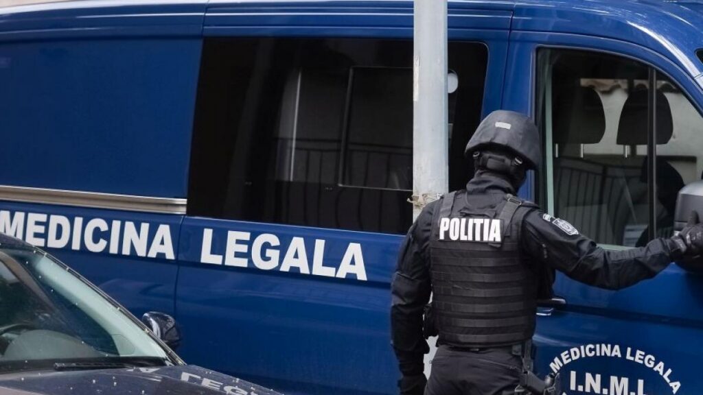 Italian police officer in tactical gear by a blue van labeled 'Medicina Legale', door open, as if securing a scene