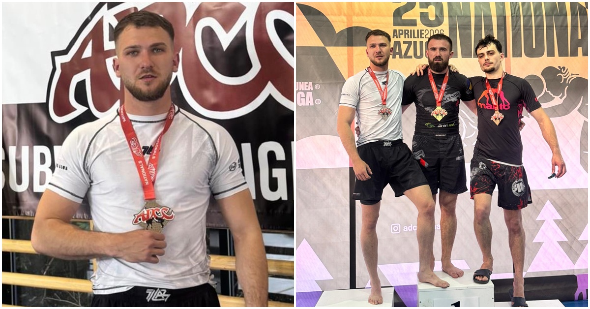 Male athlete posing with a red medal in a white shirt, standing in front of an event banner indoors.