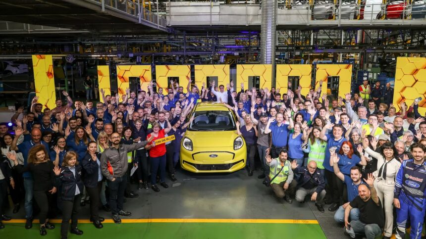 Factory workers celebrate around a yellow Ford Puma, holding a 'PUMA ONE MILLION' sign in an automotive plant.