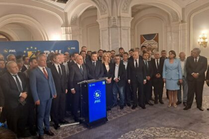 Group of suited politicians and staff pose at a press event around a blue podium with the PNL logo in a grand room.