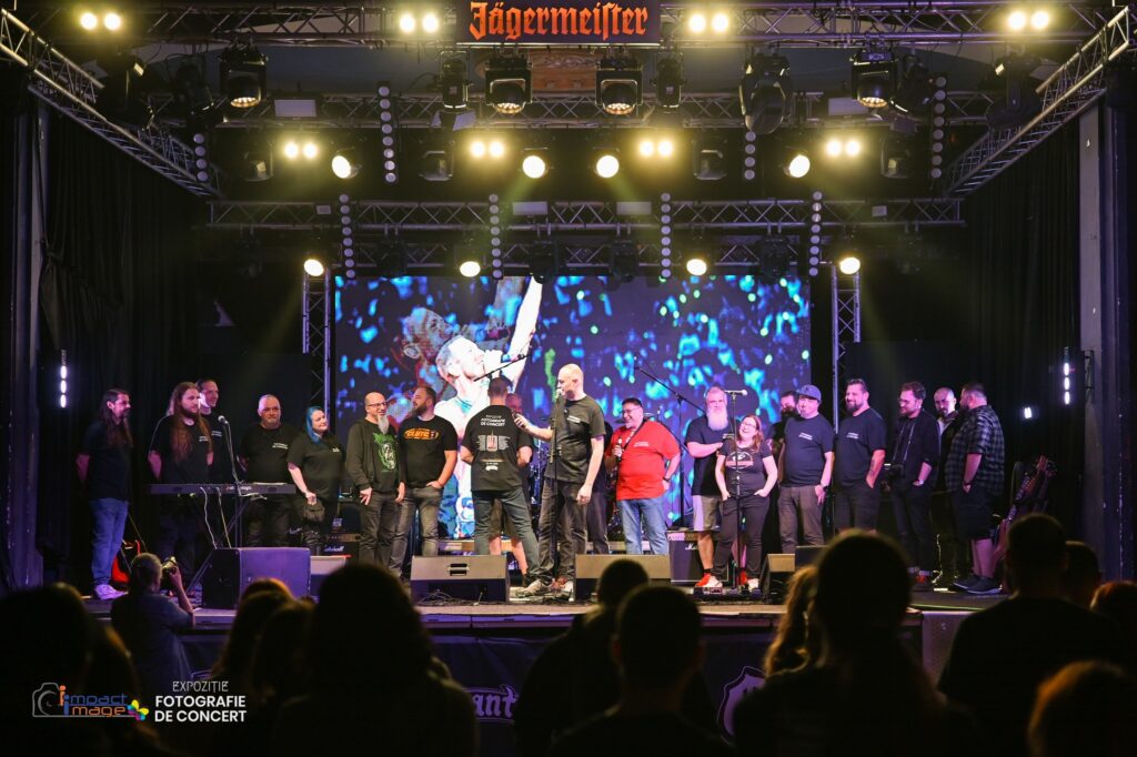 Group of performers on a stage with a bright LED screen backdrop; a Jägermeister banner overhead and audience silhouettes in the foreground.