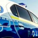 Romanian police car photographed from the side with blue and white livery, emergency 112 mark, and blue roof light