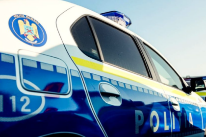 Romanian police car photographed from the side with blue and white livery, emergency 112 mark, and blue roof light