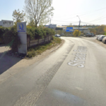 Curved road with parked cars on the right and a building labeled Registrul Auto Român on the left.