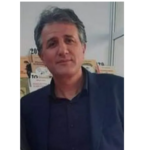 Middle-aged man with salt-and-pepper hair wearing a dark blazer, indoors, looking at the camera.