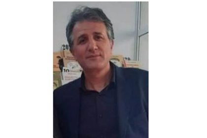 Middle-aged man with salt-and-pepper hair wearing a dark blazer, indoors, looking at the camera.