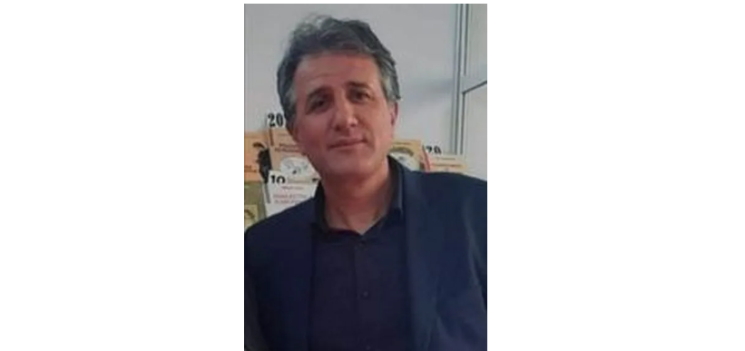 Middle-aged man with salt-and-pepper hair wearing a dark blazer, indoors, looking at the camera.