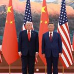 Two world leaders, Donald Trump and Xi Jinping, stand side by side in front of alternating U.S. and Chinese flags during a formal event.