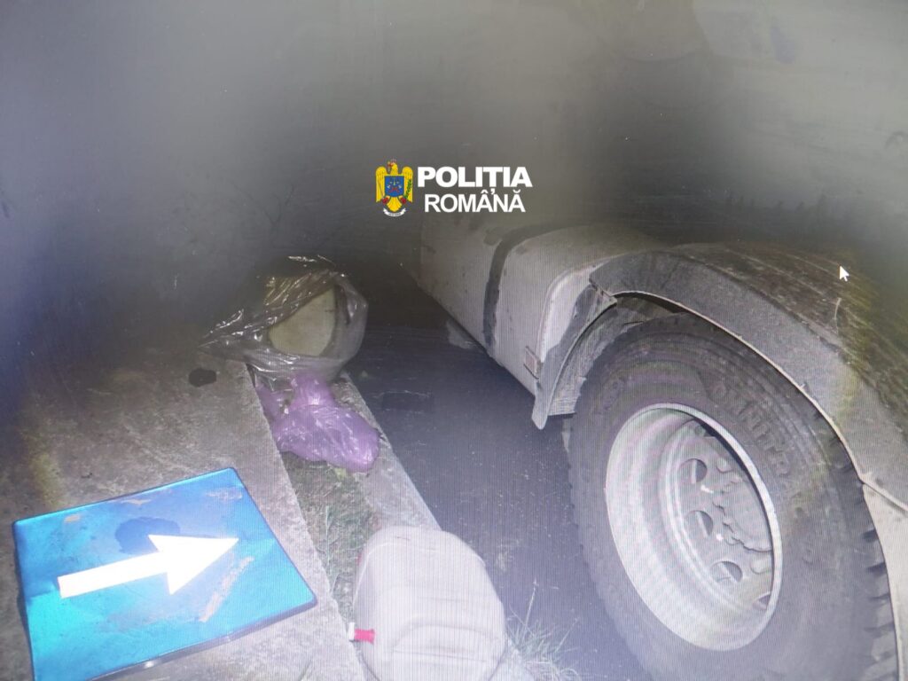 Police car crash scene at night with a damaged front wheel and a blue traffic sign on the ground; Romanian police watermark visible.