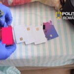 Two gloved hands arrange several white and purple smart cards with gold chips on a striped surface, with DIICOT and Romanian police logos visible.