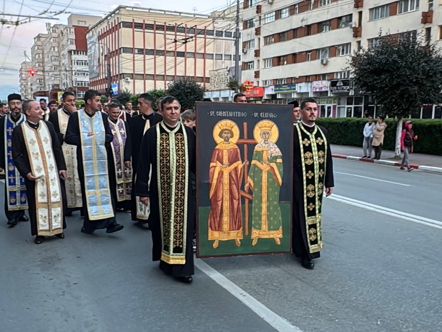 - Jurnalul Olteniei – Știri din Craiova și Oltenia Orthodox priests in colorful ceremonial robes marching down a city street, carrying a large icon of two saints in the foreground.