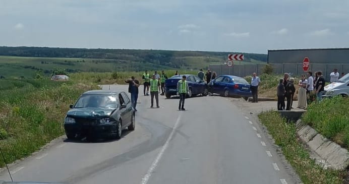 accident dj 546 brebeni WhatsApp Image 2026-05-23 at 123202 - Jurnalul Olteniei – Știri din Craiova și Oltenia Group of people in high-visibility vests and bystanders gather around parked cars on a rural curved two-lane road after a crash, with open fields in the background.