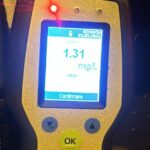 Handheld breathalyzer displaying a 1.31 mg/L breath alcohol level with a red LED indicator and an 'OK' button.
