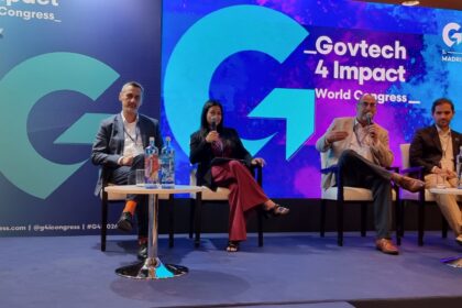 Panel of four speakers seated on a stage during Govtech 4 Impact World Congress, with a blue, illuminated backdrop and large event branding behind them.