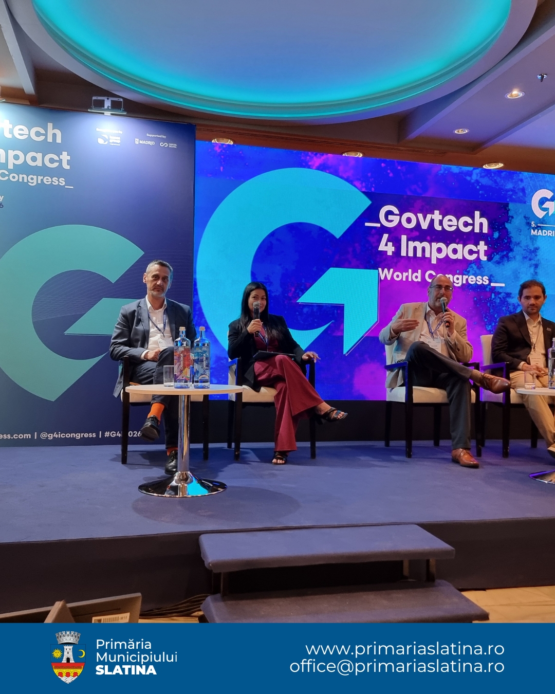 Panel of four speakers seated on a stage during Govtech 4 Impact World Congress, with a blue, illuminated backdrop and large event branding behind them.