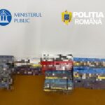 Stacks of boxed items on a table in a room with the Romanian Ministry of Public Affairs and Police logos on the wall.