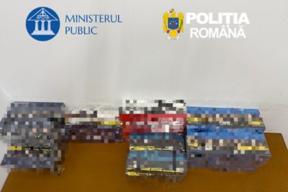 Stacks of boxed items on a table in a room with the Romanian Ministry of Public Affairs and Police logos on the wall.