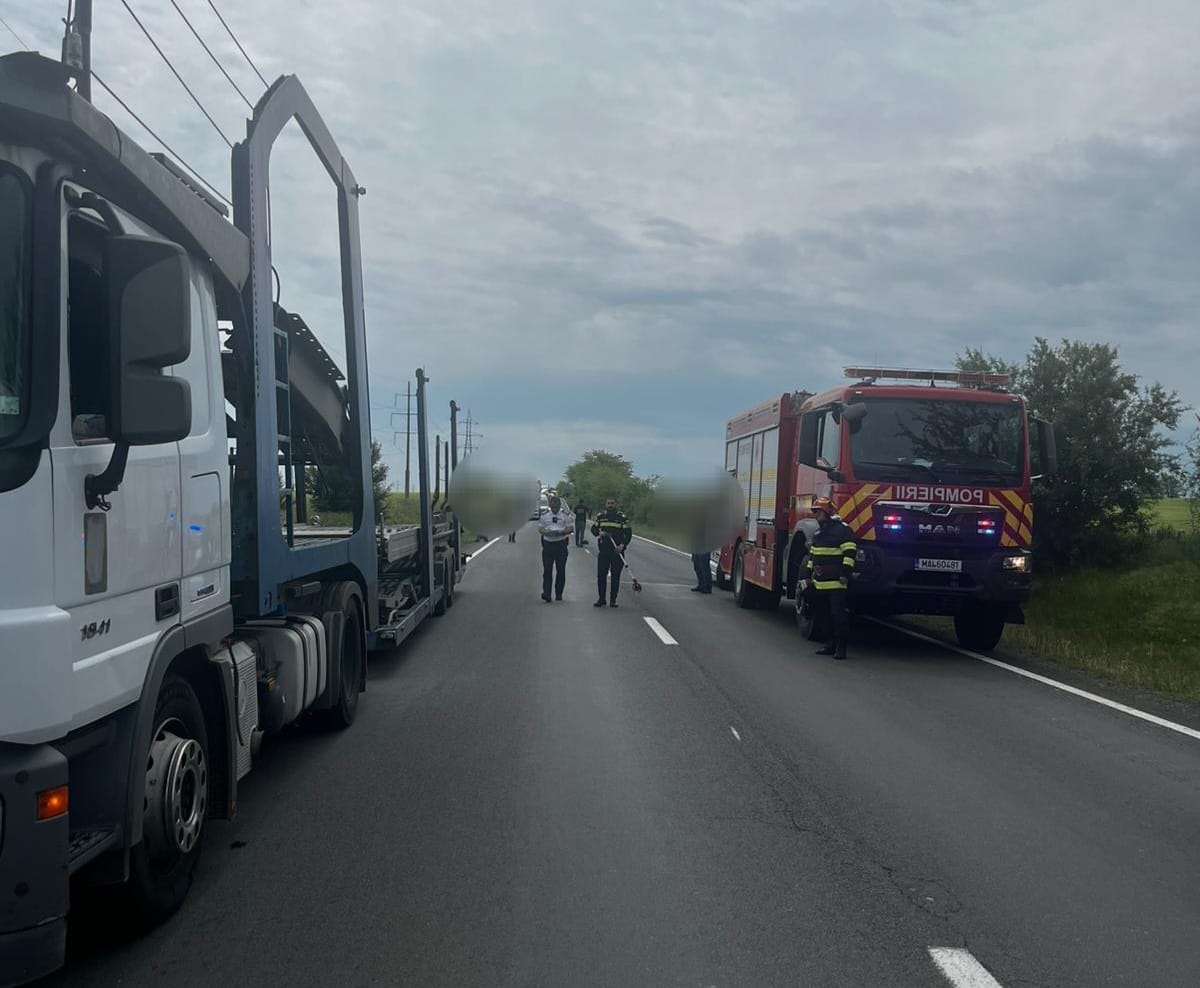 Emergency scene on a two-lane road with a large truck on the left and a red fire truck on the right; responders stand in the road.