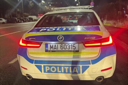 Rear view of a Romanian police car at night with POLITIA lettering and blue-yellow markings on the trunk area.