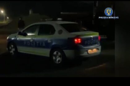 Romanian Police car at night with blue-and-white livery and red taillights visible.
