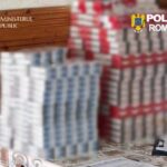 Blurred stacks of packaged goods on a table, with official logos from the Romanian Public Prosecutor's Office and Romanian Police in the corners.
