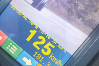 Car dashboard screen showing current speed 125 km/h and distance 181.3 m on a blue/orange display with a truck ahead on a road.