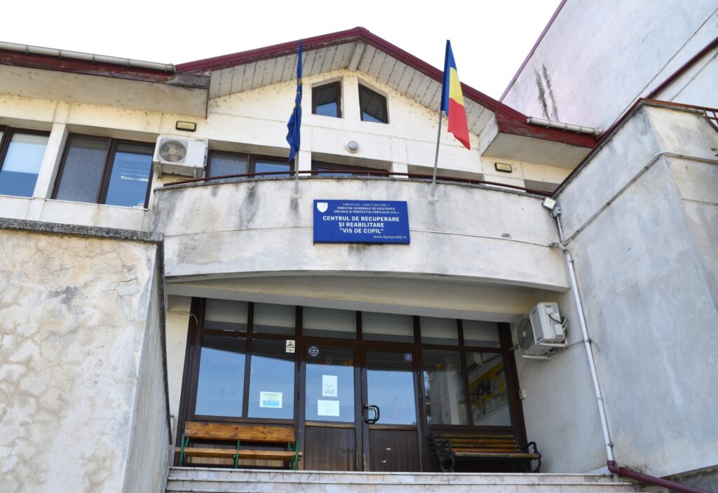 Centrul de Recuperare și Reabilitare „Vis de Copil” entrance with two flags (EU and Romania) above glass doors.