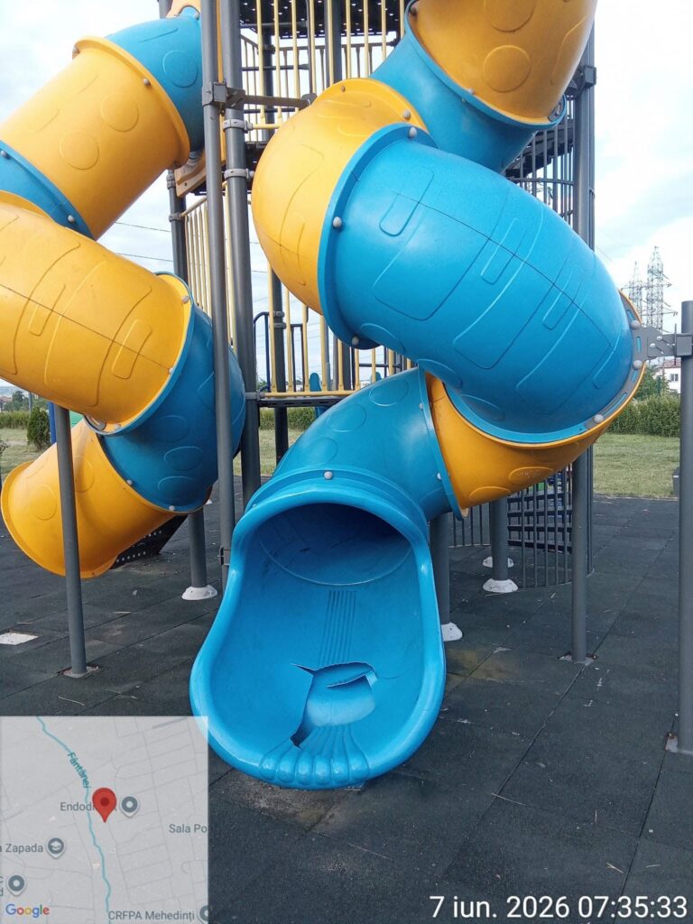Multicolored blue and yellow enclosed playground slides twisting around metal supports outdoors at a park.
