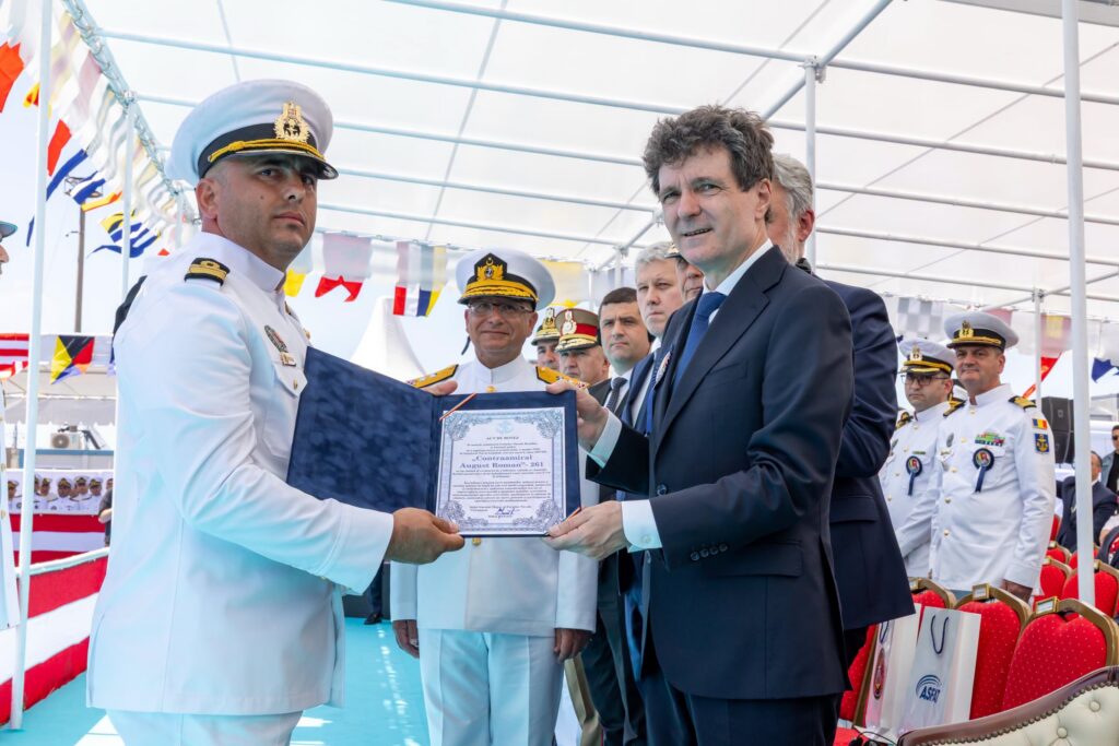 - Jurnalul Olteniei – Știri din Craiova și Oltenia Two men exchange a framed certificate during a formal ceremony, with naval officers and flags in the background.