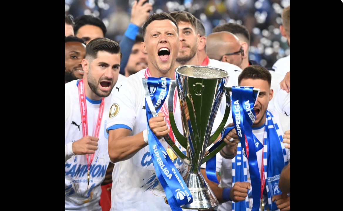 Soccer players celebrate with a large trophy and blue ribbons after winning a championship