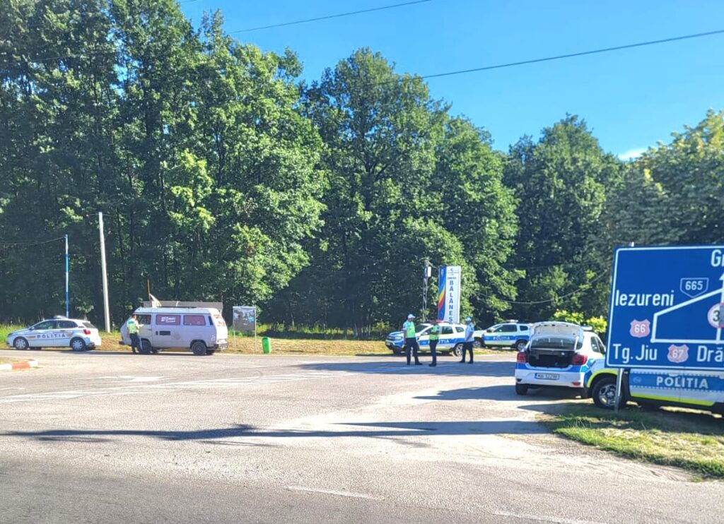 WhatsApp Image 2026-06-22 at 144039 1 - Jurnalul Olteniei – Știri din Craiova și Oltenia Police cars and officers at a roadside checkpoint among trees on a sunny day.