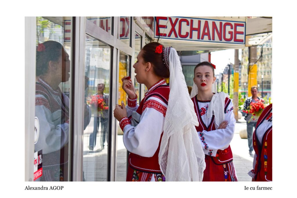 Two women in red-and-white traditional dresses with white veils stand by a glass storefront; one applies lipstick while looking into the window, reflection visible in the glass.