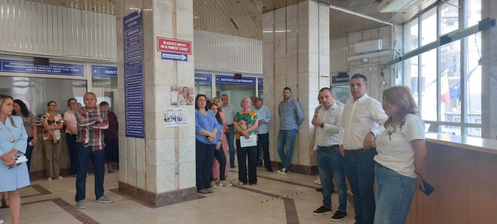 Group of people standing in a marble-walled government office lobby, waiting near counters.