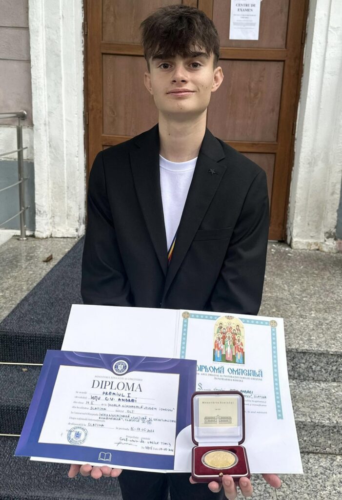 Young graduate in a black blazer holds a diploma folder and an open medal case outdoors.﻿