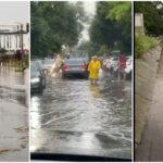 City street heavily flooded after rain, with cars and debris in water along the curb.