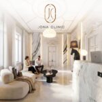 Luxurious white marble clinic lobby with two people seated on a sofa, chatting under the JONA CLINIC logo.