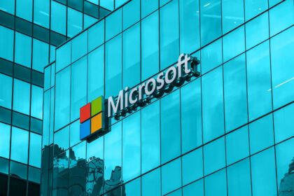 Microsoft logo on a blue glass office building façade, sign mounted on the exterior glass wall