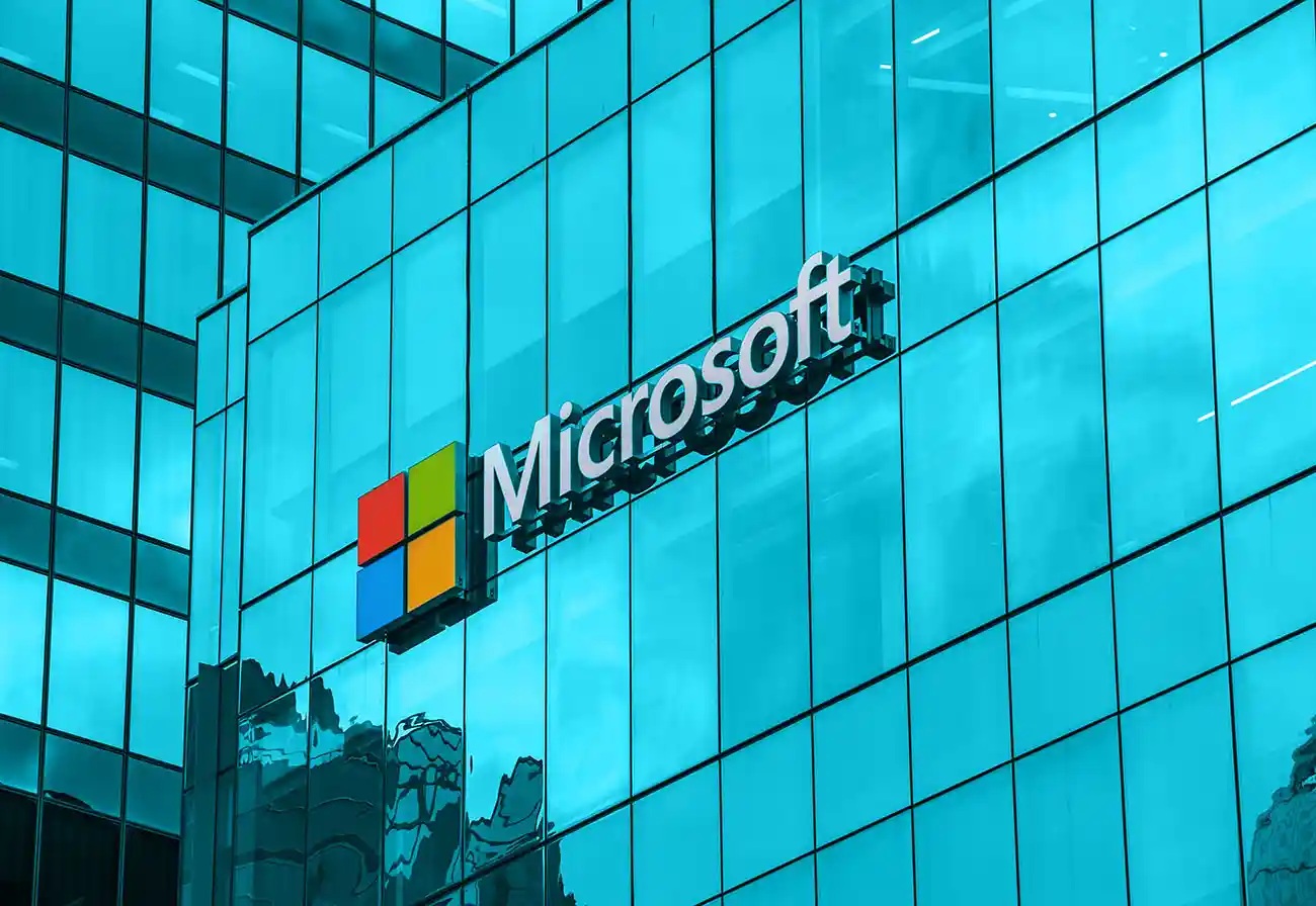 Microsoft logo on a blue glass office building façade, sign mounted on the exterior glass wall