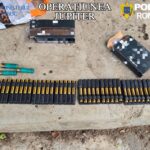 Row of black cartridge holders with gold-tipped bullets and a few green shotgun shells on a concrete surface, with opened boxes nearby and 'OPERATIUNEA JUPITER' and 'POLIŢIA ROMÂNĂ' branding