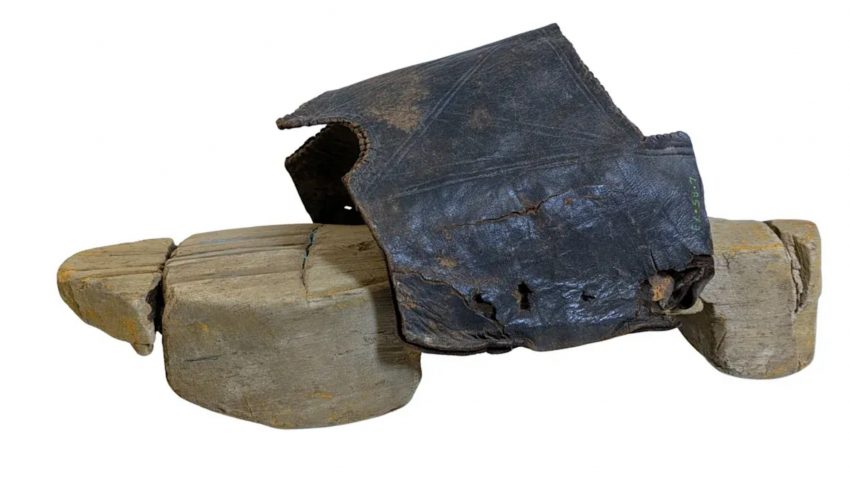 Charred black leather glove draped over stacked clay bricks.