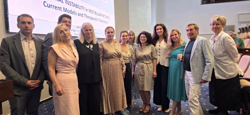 poze simpozion laquer - Jurnalul Olteniei – Știri din Craiova și Oltenia Group of professionals in formal attire posing for a photo in a conference room, with a presentation screen in the background.