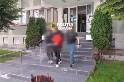 Entrance of a police building with 'Politia Romana' sign; blurred individuals descend concrete steps.