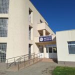 Beige modern hospital building with curved glass block windows and a ramp to the entrance.